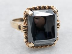 This lovely ring is crafted of polished yellow gold, with four prongs holding the stone securely. The center is a faceted, perfectly polished rectangle of Hematite, a highly reflective dove-gray stone with plenty of shine! Hematite is said to ground the energies of the wearer, preventing stress or worry. Metal: 10K Yellow Gold Gem: Hematite 10.50 Carats Gem Measurements: 12.0 x 14.1 mm, Rectangle Ring Size: 6.25 Marks: "10K{R/S}" Stamped on the inside band SKU #: A50345 Each piece has been identified and graded by a Graduate Gemologist who has been certified by the Gemological Institute of America (GIA). We have six brick-and-mortar storefronts in Maine, Massachusetts and New Hampshire and have been in business for over 25 years! Please visit our Shop's About Page or our website for more i Hematite Jewelry, Hematite Ring, Lovely Ring, Grey Stone, Ring Vintage, New Hampshire, Yellow Gold Rings, Estate Jewelry, Rings Statement