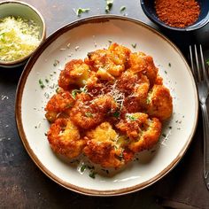 a white plate topped with fried food next to bowls of seasoning