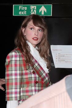 a woman standing in front of a fire exit sign