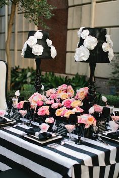 a table topped with black and white striped tables cloths covered in pink and white flowers