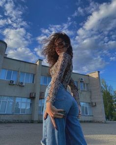 a woman standing in front of a building with her back to the camera and arms around her body