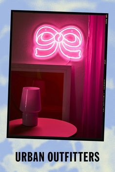 a pink lamp sitting on top of a table in front of a neon sign that says urban outfitters