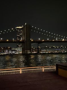 the city skyline is lit up at night by the water's edge with lights on