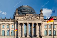 an old building with flags flying in front of it and a dome on the top