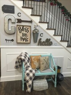 a blue bench sitting under a staircase next to a wall with letters and decorations on it