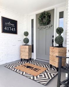 a front door with two planters and a welcome mat on the floor next to it