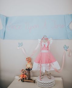 a pink and white dress sitting on top of a table next to a stuffed animal