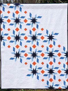 an orange and blue quilt hanging on a fence