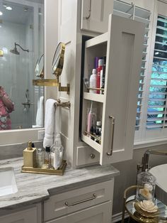 a bathroom with white cabinets and marble counter tops, along with an open medicine cabinet