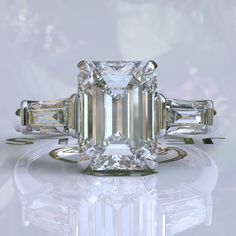 an emerald - cut diamond ring with three baguets on the side, surrounded by diamonds