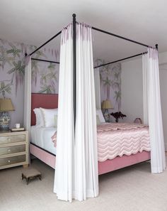 a canopy bed with white drapes and pink bedspread in a purple bedroom