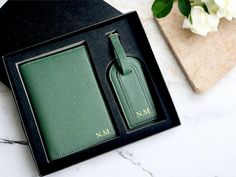 two green luggage tags in a black box on a marble countertop next to flowers