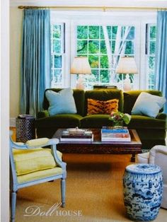 a living room with blue and white furniture in front of a large window that looks out onto the yard