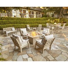 an outdoor fire pit surrounded by chairs and tables