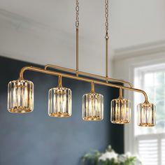 a chandelier with four lights hanging from it's sides in a living room