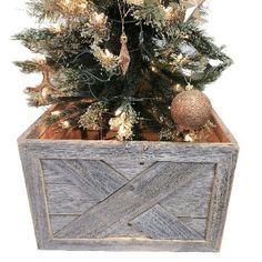 a christmas tree in a wooden box with lights and ornaments on it's sides