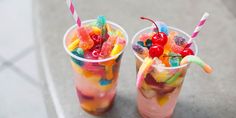 two cups filled with jelly beans and gummy bears on top of a table next to each other