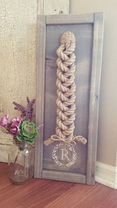 a vase filled with flowers sitting next to a roped up frame on top of a wooden floor