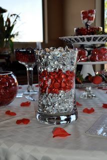 a table topped with lots of red candies next to wine glasses and plates filled with candy