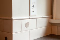 an electrical outlet on the side of a wall in a room with tile flooring