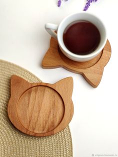 two wooden coasters with cats on them next to a cup of coffee and lavender flowers