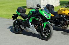 two motorcycles are parked next to each other on the street in front of some grass