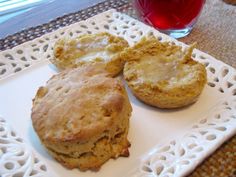 three biscuits on a white plate next to a glass of red wine and a cup of tea