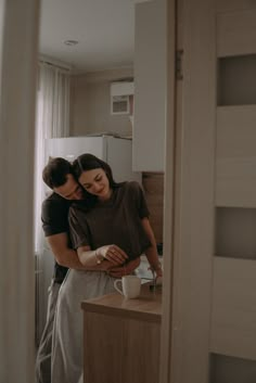 a man and woman standing next to each other in a kitchen