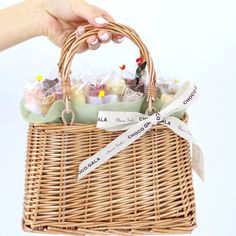 a hand holding a wicker basket filled with small candies and candy bar wrappers