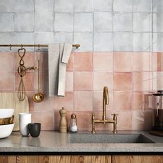 a kitchen with pink tiles and gold faucets on the counter top next to a sink