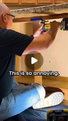 a man sitting on the floor fixing a cabinet