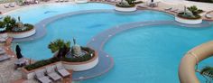 an outdoor swimming pool surrounded by lounge chairs