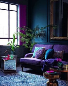 a living room filled with purple couches and pillows next to a large painting on the wall