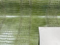 a white piece of paper sitting on top of an alligator skin pattern wallpaper covered in green crocet