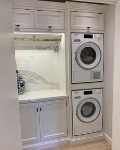 a washer and dryer in a white laundry room with marble counter tops on the wall