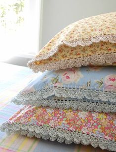 a stack of pillows sitting on top of a bed covered in lacy doily and crochet