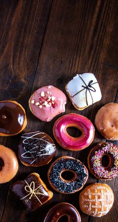 many different types of doughnuts on a wooden table