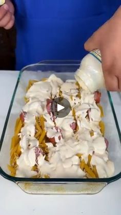 someone is pouring dressing into a casserole in a glass dish on a table