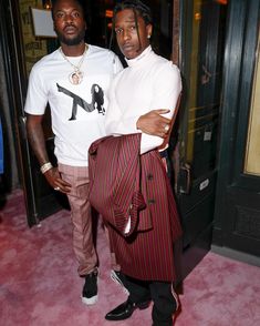 two men standing next to each other in front of a door with pink carpet on the floor