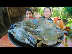 two women sitting at a table with some crabs on it