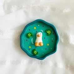 a green plate with a white bear on it's side and flowers in the middle