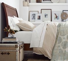 a bed with white sheets and pillows in a bedroom next to pictures on the wall