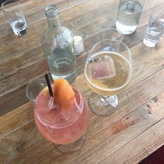 there are three glasses on the table and one has an orange in it, while the other is empty