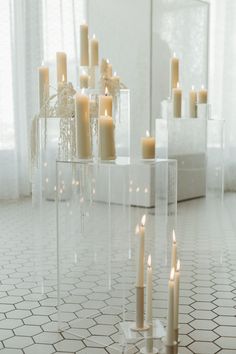 candles are arranged in clear vases on the floor