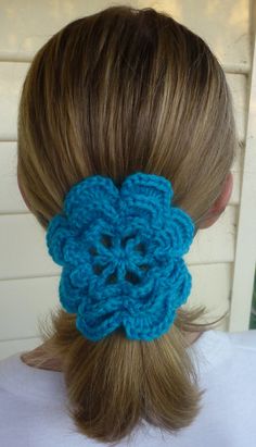 a woman with blonde hair wearing a blue crochet flower in the back of her head