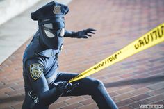 a person in a mask and police uniform holding a yellow caution tape on the ground