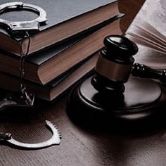 a judge's gavel, book and handcuffs on a wooden table next to a pair of scissors