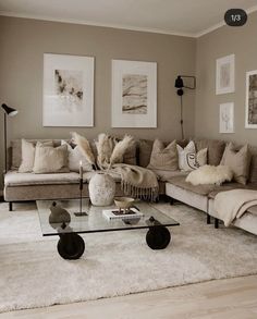 a living room filled with lots of furniture and pictures on the wall above it's glass coffee table