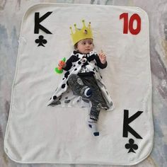 a baby wearing a crown laying on top of a playing card