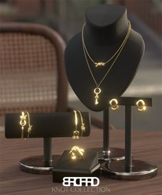 three necklaces and two rings on display in front of a table with a hat